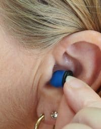 Woman inserts ear plugs.