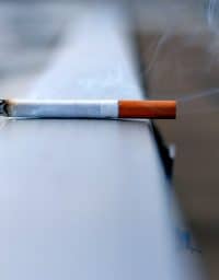 A lit cigarette sitting on a ledge