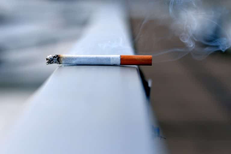A lit cigarette sitting on a ledge