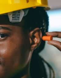 Female construction worker using earplugs as hearing protection.