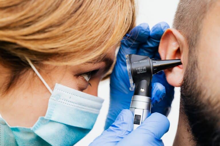 Doctor performing an ear exam on man with tinnitus.