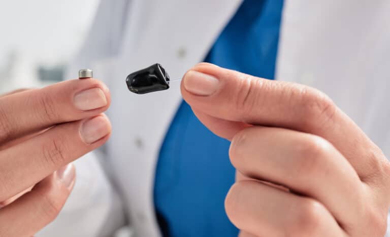 Audiologist holding a small hearing aid and battery