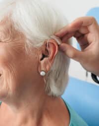 Senior woman getting a new hearing aid put on