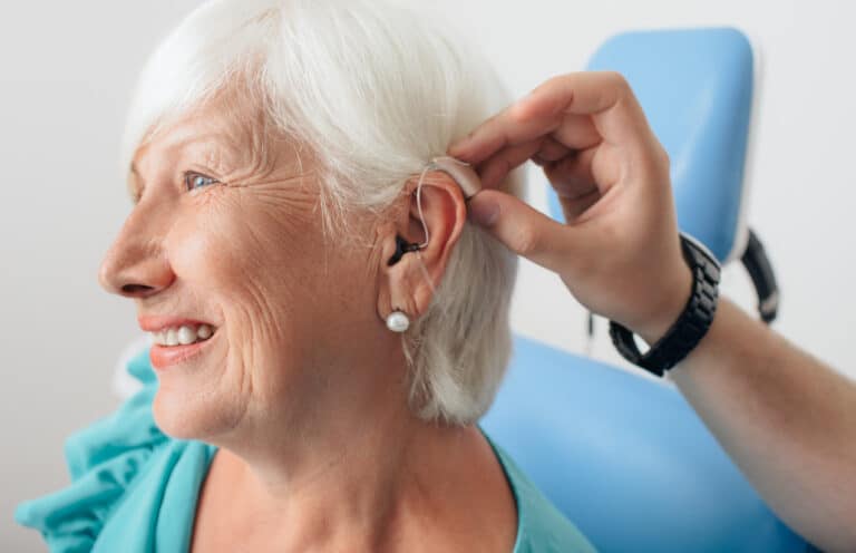Senior woman getting a new hearing aid put on 