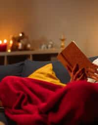 Young woman reading a book on sofa at home during christmas time